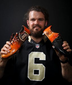 New Orleans Saints Punter Thomas Morstead Holding his cleats for the My Cause, My Cleats campaign featuring Triumph Over Kid Cancer